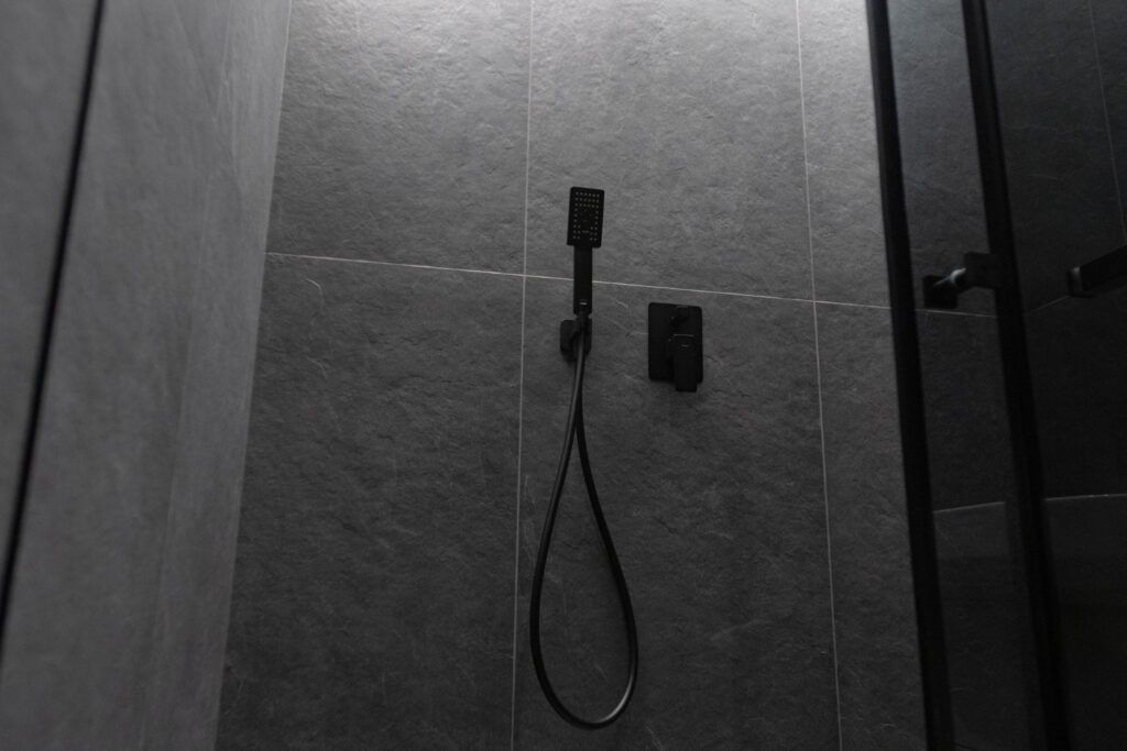 Coloană duș de culoare negru mat, într-o baie în stil industrial.